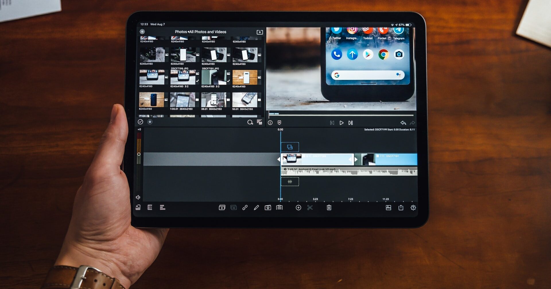 Person holding a black tablet showing a video editing software.