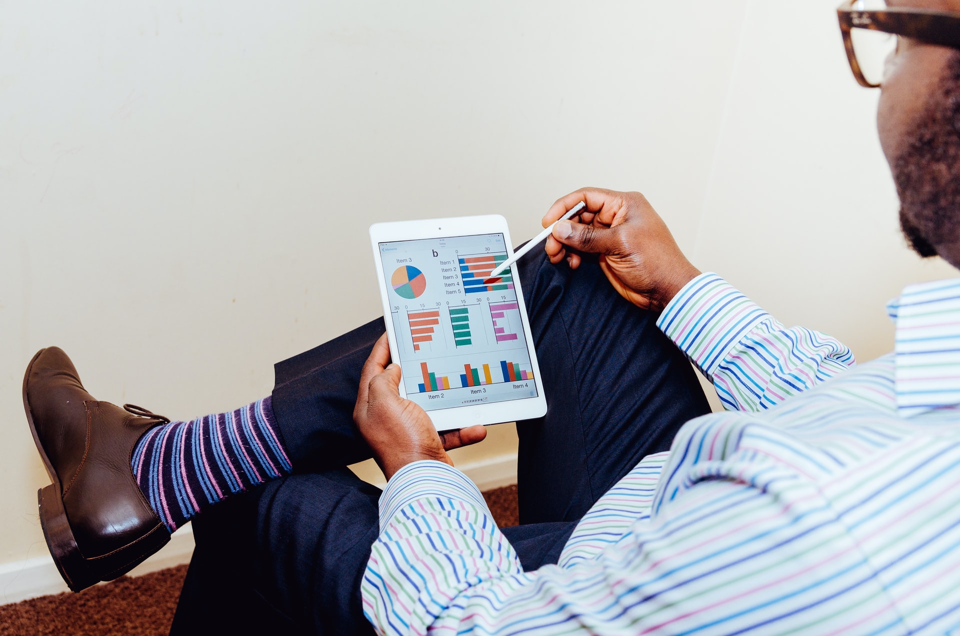 A person sitting on a chair holding an iPad to check invoice software report.