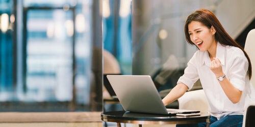 woman using a laptop celebrating landing her business idea